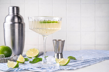 Summer cold refreshment limeade cocktail, cold alcohol or non-alcohol beverage with limes, mint and ice cubes, copy space