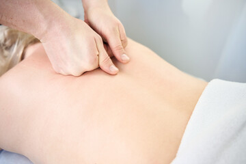 Masseur giving upper back massage to client