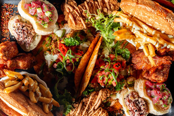 Assorted fast food items including burgers, fries, and fried chicken, arranged on a wooden table. Perfect for illustrating concepts of fast food, casual dining, and indulgence