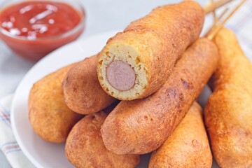 Corn dogs on white plate, served with ketchup, horizontal closeup