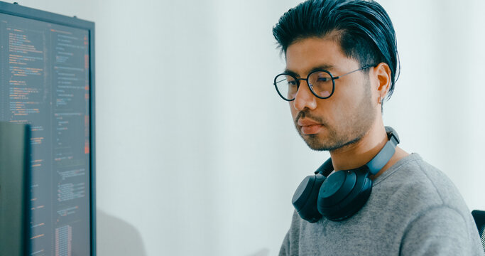 Young adult Asia male freelance eyeglasses typing write prompt AI bot IT app smart program nomad, video game, terminal with coding, user interface, designer, big data center on desktop computer.