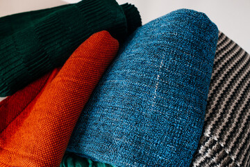 A stack of warm, knitted blankets in various colors and patterns, ideal for cozy and home-related visuals.