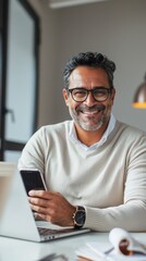 A man wearing glasses is smiling and holding a cell phone