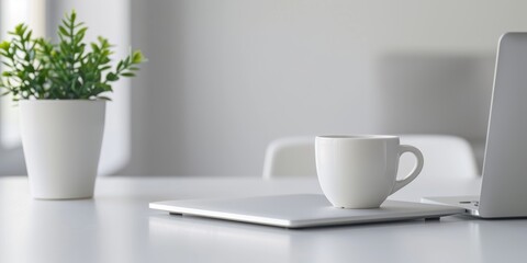 Obraz premium modern white desk with an open laptop and coffee cup, blurred background of a minimalist home office