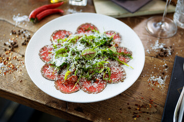 Beef carpaccio. Borettane onion, sun-dried tomato, truffle dressing, arugula salad, parmesan cheese. Italian traditional antipasti snacks served for lunch with wine in modern gourmet restaurant