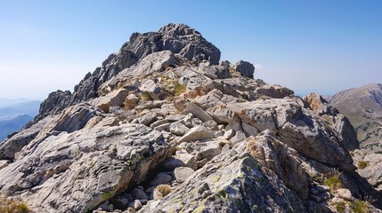 The rocky summit of a mountain with a clear, blue sky overhead.