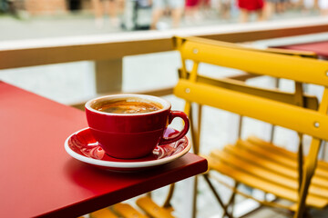 A red cup of black coffee on a cafe terrace