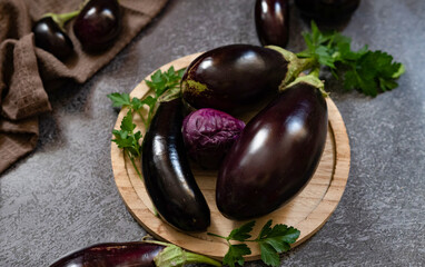 Fresh mini eggplant in a wooden plate on a white wooden background. Vegetables.