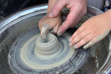 Potter helps to the child at a pottery master class.