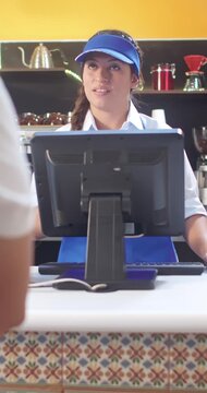 Close-up vertical shot for social media, of a Latina woman touching a monitor where she manages food orders requested by customers.