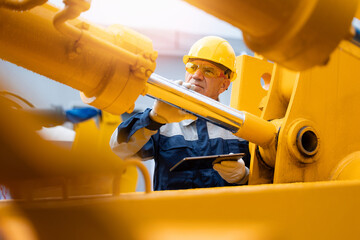 Mechanic operator with tablet computer check hydraulic piston of hose system equipment on excavator. Industry engineer of machinery tractor © Parilov