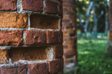 Old, ruined red brick columns. The entrance to the old, ruined stable