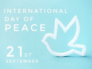 A poster with text for the International Day of Peace, celebrated on September 21st, featuring a white wooden dove symbolizing peace against a light blue background