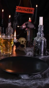The witch's hand lights a candle and puts a Monster Burger on the festive table in honor of Halloween. Vertical video, real time.