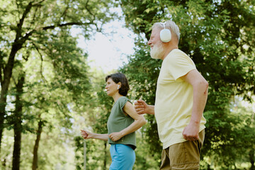 Senior couple listening to music via wireless headphones while running