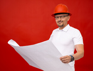 A male engineer in a white t-shirt and a red helmet is holding a large white sheet with a...