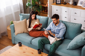 Obraz premium Couple reading and drinking coffee at home