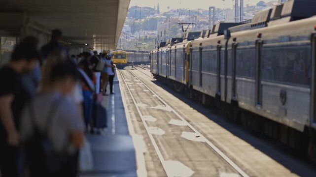 A train is pulling into a station with people waiting to board