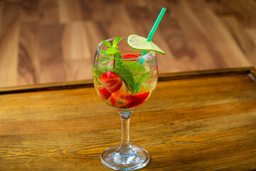 Glass with non-alcoholic cocktail strawberry mint lime with ice on wooden table