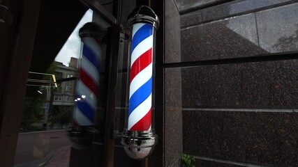 Barbershop pole outside a storefront in the city during the evening