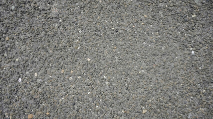 A close-up view of textured asphalt showing various stones during daylight hours