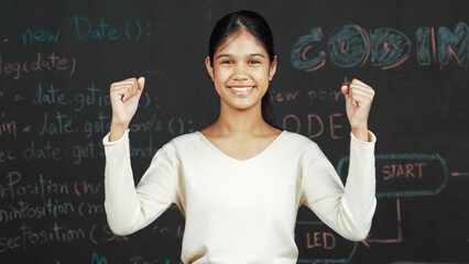 Young student celebrate her successful plan while raise her arm. Happy teenager looking at camera...