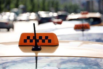 Taxi top sign and antenna on yellow car roof on blurred road background, transport in city