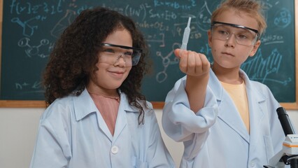 Curious american student standing at blackboard with chemical theory while doing experiment and...
