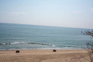 two atvs riding along on a cape cod beach in Massachusetts