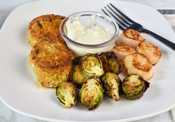 crtwo crab cakes served with sheared scallops