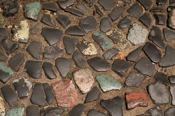 A close up of a cobblestone path with faded paint The uneven surface adds texture and character