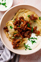 Polish dumplings with fried chanterelles and sour cream on a plate..style hugge.