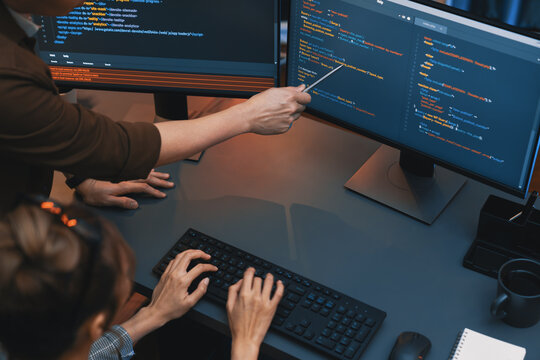 Top view of IT developers discussing with point to intelligent website development coder system running data online two screens information technology at neon light room at modern office. Infobahn.