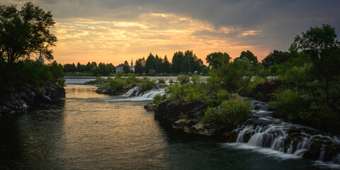 The Heart of Idaho Falls over the Snake River Waterfront at Sunrise in Bonneville County, Idaho, USA: The serene waterfalls flowing through the center of town