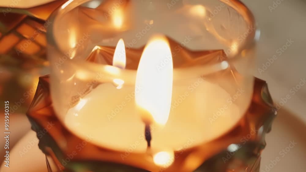 Aufkleber Detailed footage of a candle flame casting a warm glow on a delicate glass candle holder creating a cozy and inviting atmosphere.