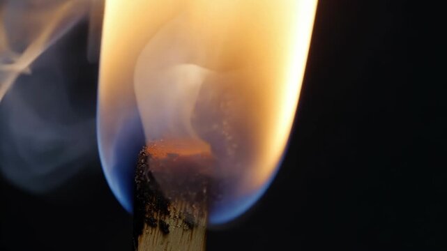 The final moments of a match as it smolders and produces thin wisps of smoke before eventually extinguishing itself.