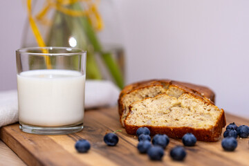 glass of milk and sweet homemade banana bread with crispy crust on a wooden board, dessert