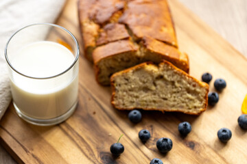 glass of milk and sweet homemade banana bread with crispy crust on a wooden board, dessert