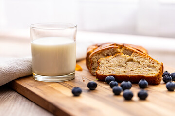 glass of milk and sweet homemade banana bread with crispy crust on a wooden board, dessert