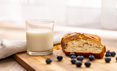 glass of milk and sweet homemade banana bread with crispy crust on a wooden board, dessert