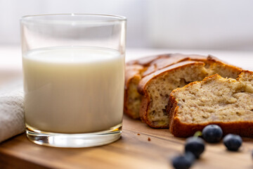 glass of milk and sweet homemade banana bread with crispy crust on a wooden board, dessert