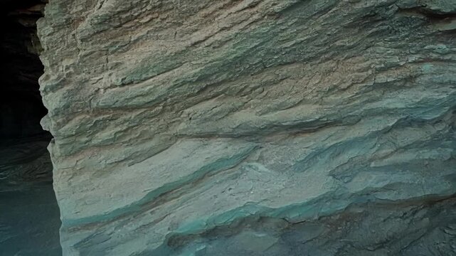 A closeup of a small cave with exposed rock strata revealing the intricate patterns and shapes of the layered rocks formed by years of erosion.
