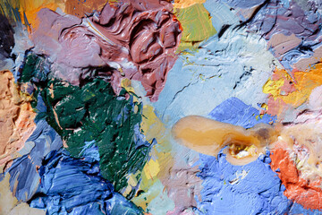 Fototapeta premium Colorful abstract texture. Smears of oil paint and a palette knife on an art palette. The concept of the modern school of art. Fragment of creative work. Colors of the year 2024