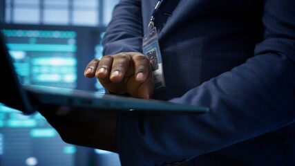 IT technician working on notebook in data center, overseeing server operations. Extreme close up shot of man ensuring optimal performance and data integrity in server hub, camera B