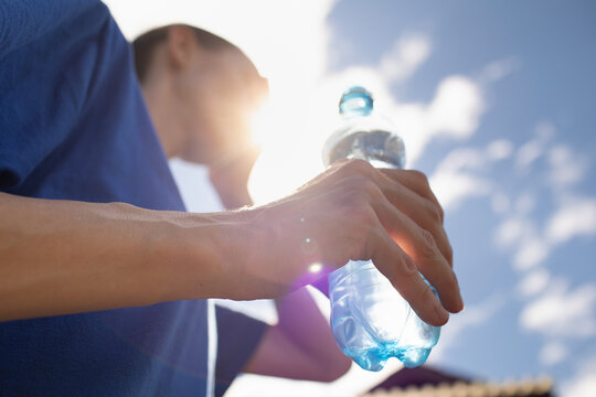 person holding bottle of water on hot sunny day 