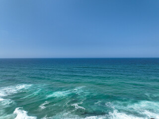 A vast expanse of turquoise ocean meets a cloudless blue sky