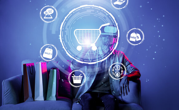 Happy man using VR headset and shopping online while sitting at sofa with shopping bags. Smart person looking at online market hologram and icon with neon background. Innovation technology. Deviation.