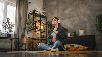 Adult woman sit on floor and have guided meditation on headphones