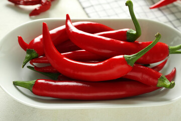 Plate of fresh chili peppers on light background