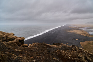 Waves crashing on black sand beach under cloudy sky in iceland
